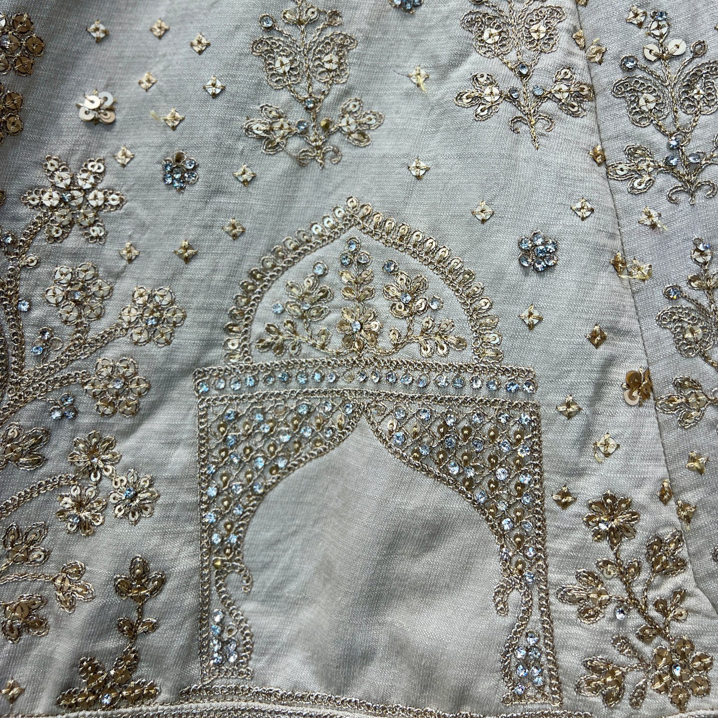 Intricate embroidery on ivory bridal lehenga showcasing floral patterns and sparkling embellishments