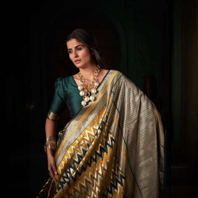 Gold silk saree with zigzag chevron pattern and silver border, styled with drape on model