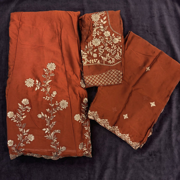 Flat lay of the rust orange rangoli silk lehenga with gold floral embroidery, the embroidered blouse and the dupatta