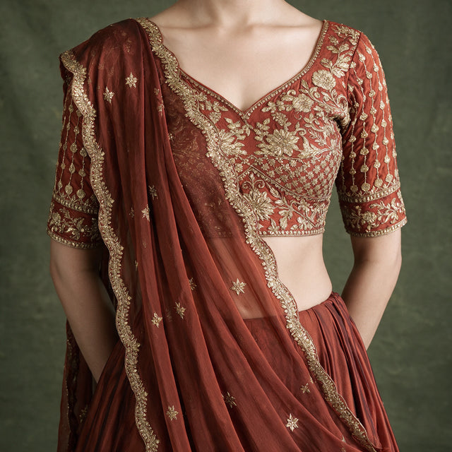 Rust choli blouse with V-neck, gold floral thread embroidery and scattered sequins