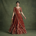 Rust embroidered lehenga choli with gold motifs and sequins, draped dupatta on model