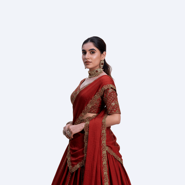 Dark red lehenga choli with gold border detailing and draped dupatta
