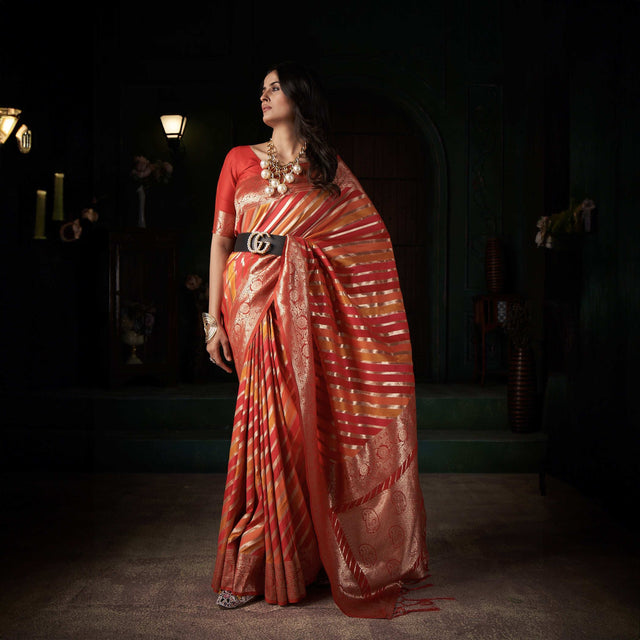 Orange silk saree with gold zari stripes and ornate woven border, draped