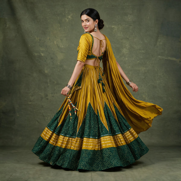Back view of the mustard and green chaniya choli in a twirl, with a tie-up blouse back, tassels and the dupatta flying
