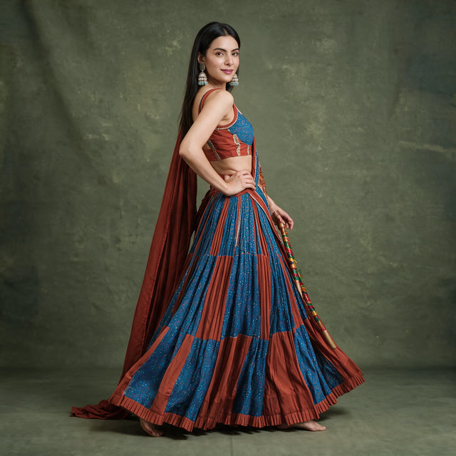 Side-back view of the rust and blue panelled skirt in a spin, with the rust dupatta trailing behind