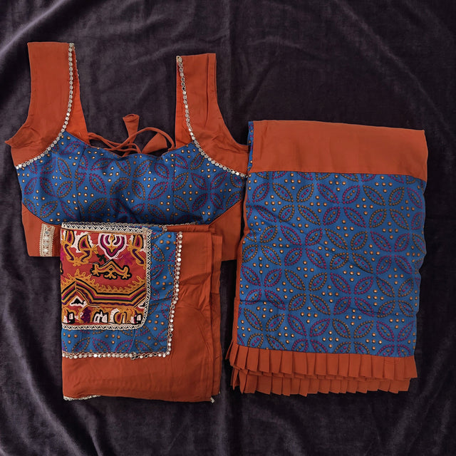 Flat lay of the blue printed blouse, the rust and blue panelled skirt and the rust dupatta with a gamthi panel