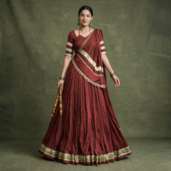 Model in a maroon pure Chanderi chaniya choli with gold zari-weave lace on the hem, blouse sleeves and dupatta, holding dandiya sticks
