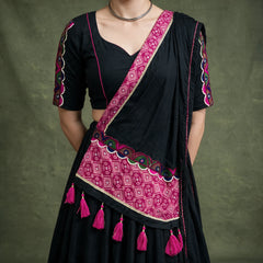 Close-up of the black blouse with embroidered sleeves and the black dupatta with a pink bandhej-print border and pink tassels