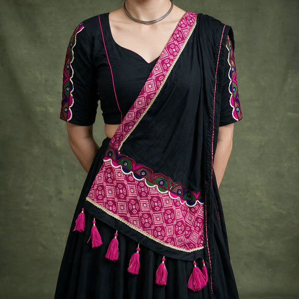 Close-up of the black blouse with embroidered sleeves and the black dupatta with a pink bandhej-print border and pink tassels