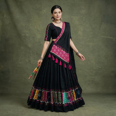 Model in a black khadi cotton chaniya choli with multicolour patchwork panels at the hem and a black dupatta with a pink bandhej-print panel and tassels