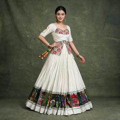 Model with a hand on her hip in the ivory chaniya choli, showing the long embroidered blouse and the multicolour hem border