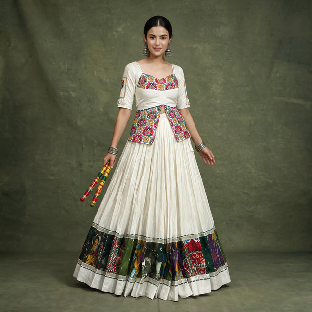 Model in an ivory khadi cotton chaniya choli with a long multicolour embroidered blouse and a multicolour panel border at the hem, holding dandiya sticks