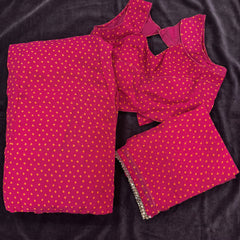 Flat lay of the magenta georgette lehenga and blouse in a bandhej print with orange dots