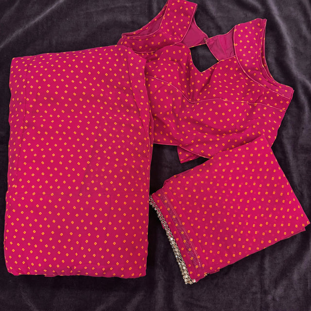 Flat lay of the magenta georgette lehenga and blouse in a bandhej print with orange dots