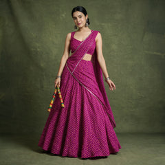 Model in a magenta georgette bandhej-print chaniya choli with a lace-edged dupatta draped across the body, holding dandiya sticks