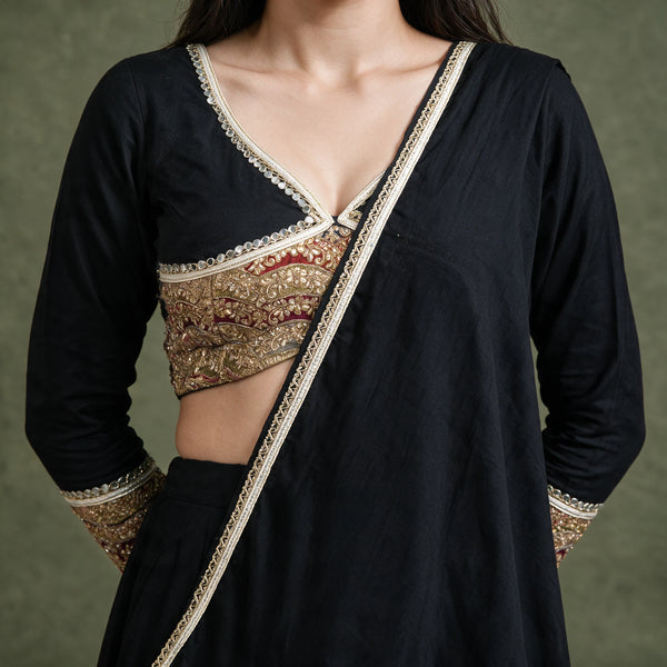 Close-up of the black blouse with a gold embroidered waist band and the dupatta draped diagonally with a cream lace edge