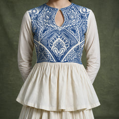 Close-up of the ivory top with a blue embroidered keyhole yoke and gathered peplum