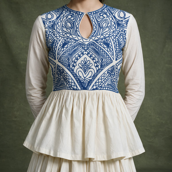Close-up of the ivory top with a blue embroidered keyhole yoke and gathered peplum