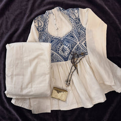 Flat lay of the ivory cotton top with a blue embroidered yoke, the ivory skirt and the small gold purse
