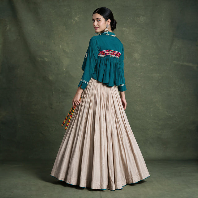 Back view of the teal jacket with a pink embroidered panel and the full beige skirt