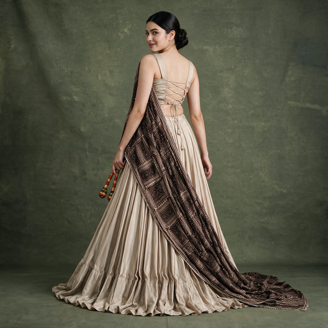 Beige pleated lehenga with lace-trimmed dark printed dupatta over satin choli