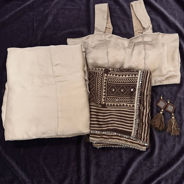 Flat lay of the beige monga silk skirt and blouse with the brown printed dupatta and tassel earrings