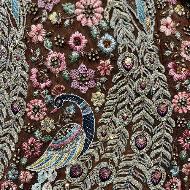 Close-up of rust lehenga fabric with peacock motif and beadwork embroidery