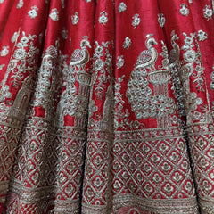 Red lehenga skirt panel with dense silver embroidery, peacock and temple-style motifs