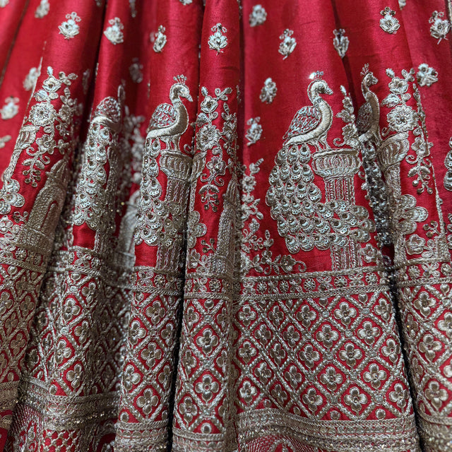 Red lehenga skirt panel with dense silver embroidery, peacock and temple-style motifs