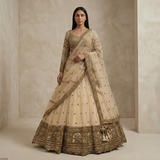 Beige embroidered lehenga with gold border, net dupatta, and tiered skirt on model