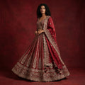 Maroon bridal lehenga with ornate gold borders, embellished blouse, and dupatta drape