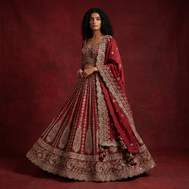 Maroon bridal lehenga with ornate gold borders, embellished blouse, and dupatta drape