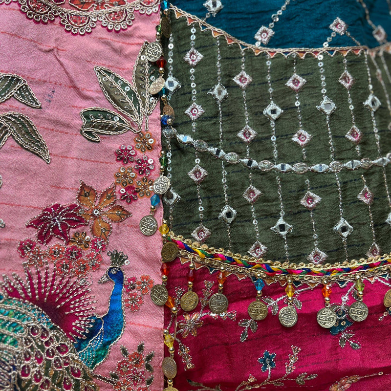 Close-up of embroidered lehenga skirt panel with teal, magenta, and bead fringe