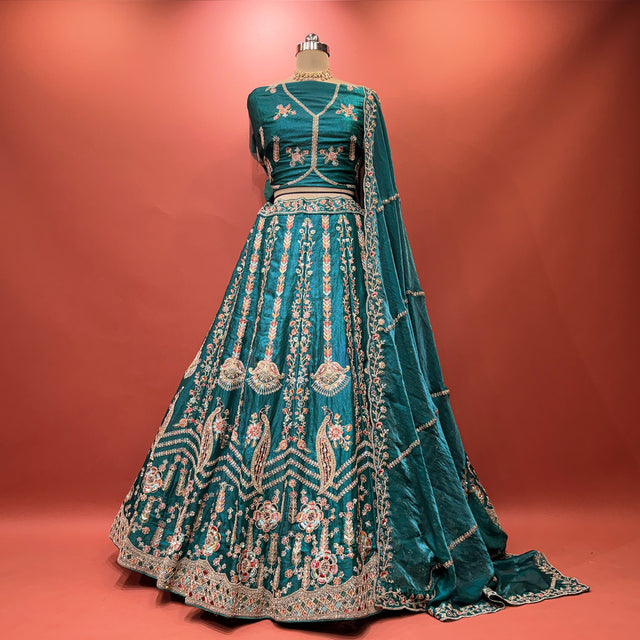 Teal embroidered lehenga with gold trim and flared skirt on mannequin