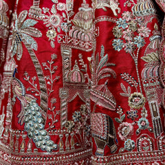 Close-up of peacock, palace, palm tree and elephant bead and zari work on red raw silk