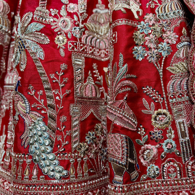 Close-up of peacock, palace, palm tree and elephant bead and zari work on red raw silk
