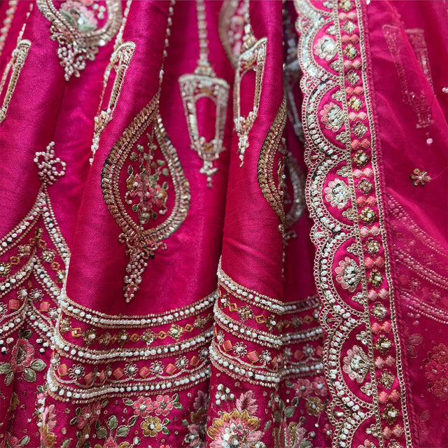 Close-up of rani pink lehenga: pearl swags, zari teardrop motifs and multicolour resham florals