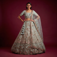 Sage green embroidered bridal lehenga set on model, with full skirt and sheer dupatta