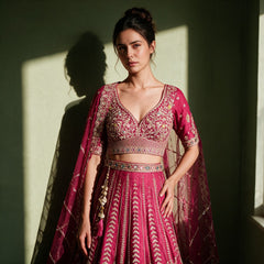 Close-up of the raspberry raw silk blouse embroidered with a floral vine, embroidered waist belt, net dupatta and latkan with pink tassels