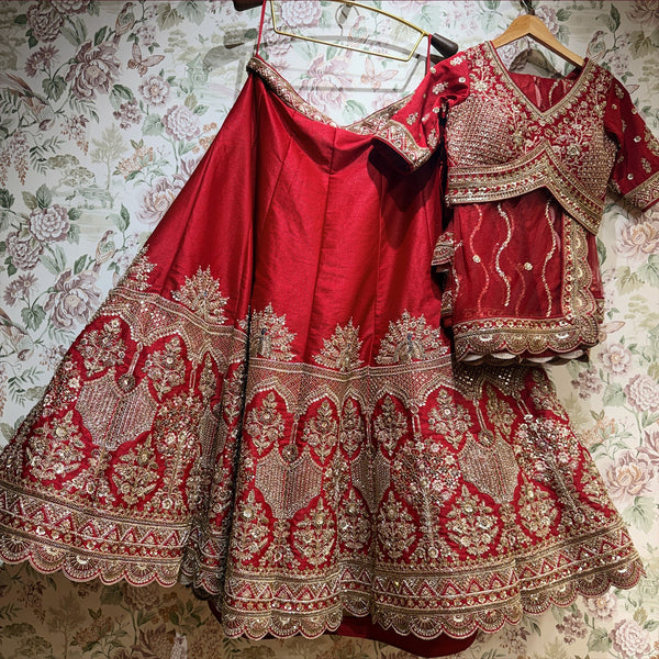 Red bridal lehenga and matching blouse on hangers with embroidered net dupatta