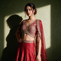 Close-up of the red raw silk cross-over blouse with lattice bodice and wide embroidered band, embroidered waistband, net dupatta and pearl latkan with red tassels
