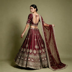 Back of a maroon raw silk blouse with scoop back and tie-up cords, gold embroidered skirt and net dupatta with scalloped border