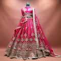Rani pink raw silk bridal lehenga with gold zari kalis, cow motif hem border and net dupatta