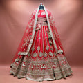 Red raw silk bridal lehenga with gold zari kalis, cow motif hem border and two net dupattas draped as a veil