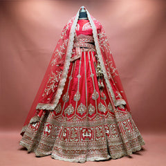 Red raw silk bridal lehenga with gold zari kalis, cow motif hem border and two net dupattas draped as a veil