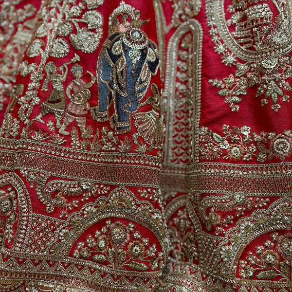 Close-up of red lehenga fabric with gold-toned elephant motif embroidery