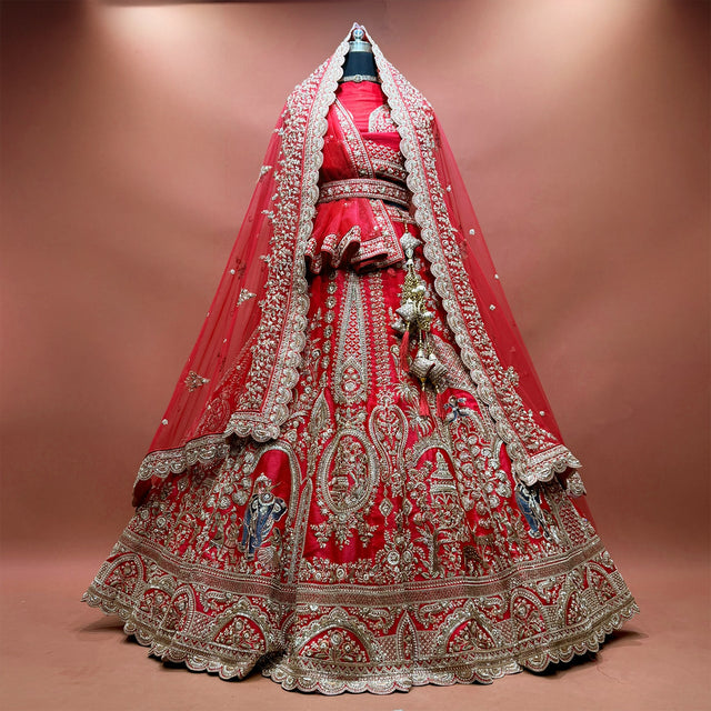 Red raw silk bridal lehenga with elephant and rider procession embroidery and two net dupattas draped as a veil