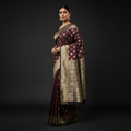 Maroon Kanjivaram-style saree with wide gold zari pallu and tassel-trimmed border drape