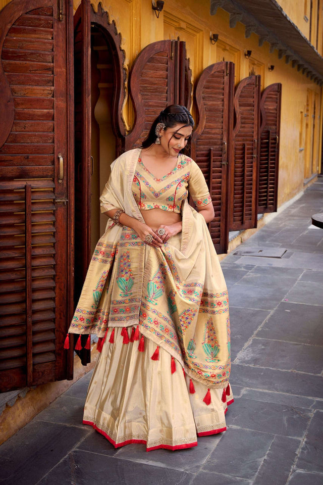 Cream lehenga choli with multicolor motifs and draped dupatta with red tassels