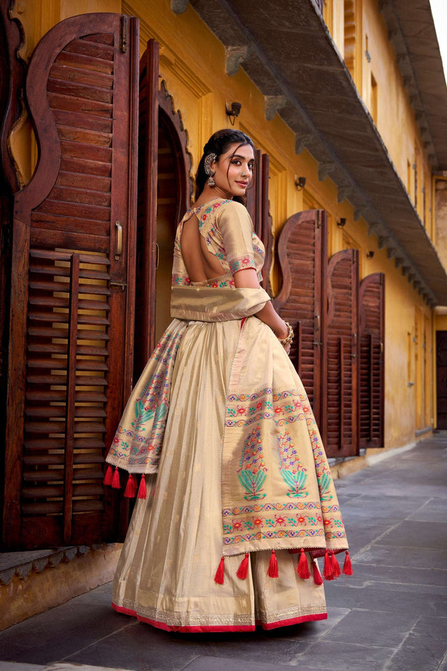 Cream lehenga choli set with wide embroidered skirt panel and red tassel border